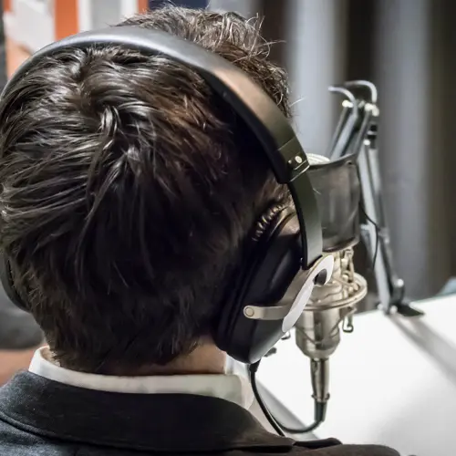 Man wearing headphones speaking into a professional podcast microphone at The Podcast Pod studio in Brentwood, TN
