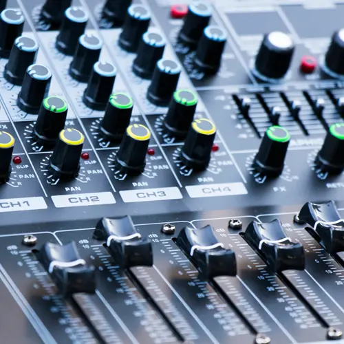 Close-up of podcast audio mixer console with channel sliders and knobs at The Podcast Pod studio in Brentwood, TN
