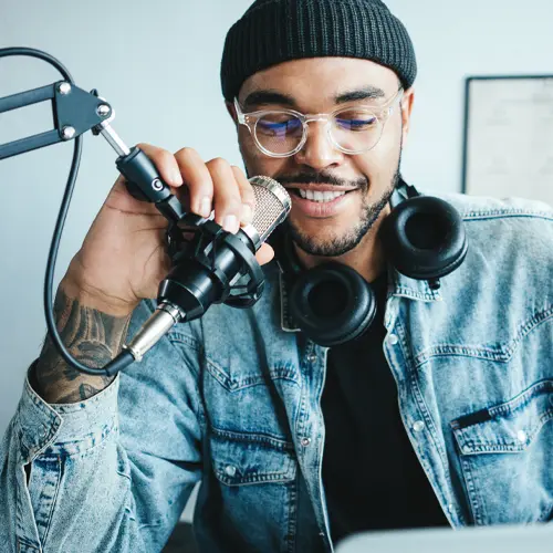 Smiling podcaster speaking into a microphone at The Podcast Pod studio in Brentwood, TN with headphones around his neck