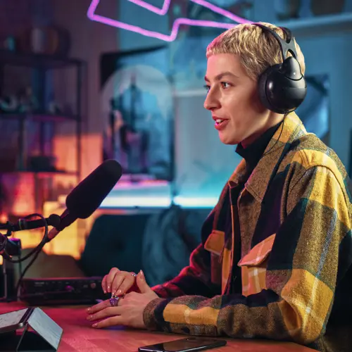 Female podcaster speaking into a studio microphone with headphones on in a modern podcast setup near Forest Hills, TN at The Podcast Pod in Brentwood