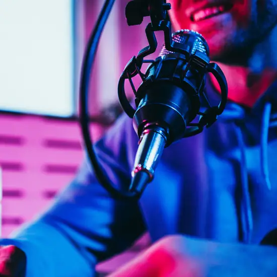 Close-up of a podcast microphone with male host smiling in a neon-lit studio near Franklin, TN at The Podcast Pod in Brentwood