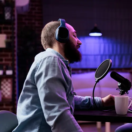 Bearded man podcasting with headphones and microphone in a purple-lit studio near Nashville, TN at The Podcast Pod in Brentwood