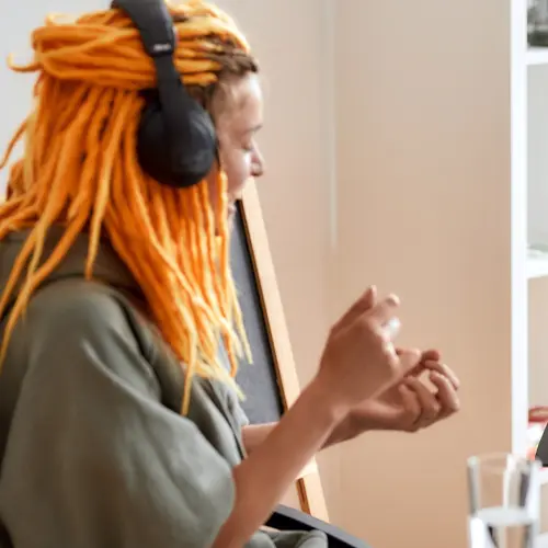 Podcaster with bright orange dreadlocks and headphones recording in studio near Nolensville, TN at The Podcast Pod in Brentwood