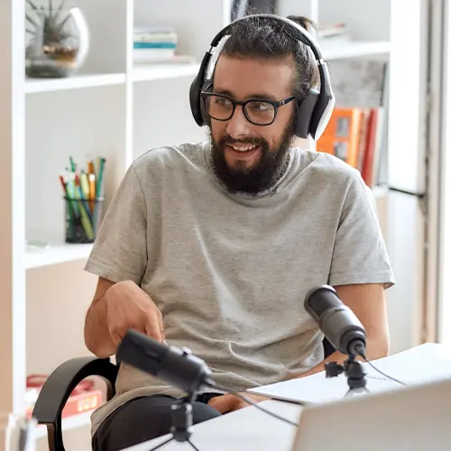 Man podcasting with dual microphones and headphones in a bright, casual studio near Nolensville, TN at The Podcast Pod in Brentwood