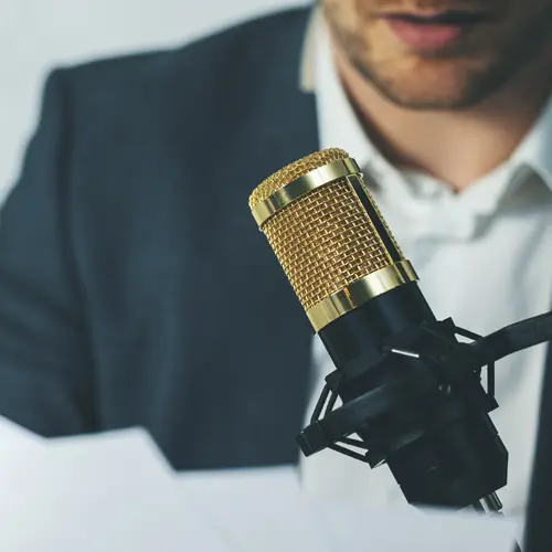 Man in a suit recording a podcast with a gold studio microphone at The Podcast Pod near Oak Hill, TN